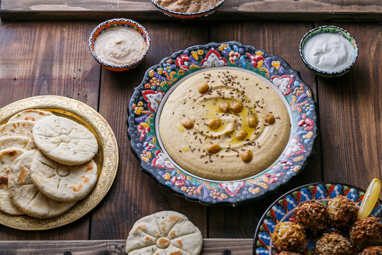 Hummus, chickpea, falafel with tahini, yoghurt and pita in traditional plate