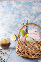 Easter cookies, bunnies and Multicolored Easter eggs in a basket on light blue background
