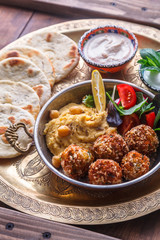 Hummus, falafel, salad and pita in a copper pan