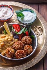 Hummus, falafel, salad in a pan with yoghurt and tahini