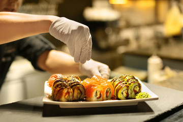 Male chef preparing sushi rolls for serving in restaurant