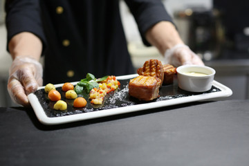 Chef with delicious grilled salmon wrapped in bacon and vegetable salsa prepared for serving in restaurant