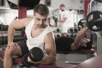 Fototapeta na wymiar Man exercising with dumbbells in gym