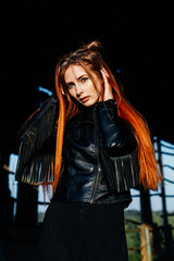 portrait of a cute red-haired girl in a black leather jacket at sunset