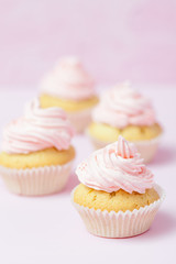 Cupcake decorated with pink buttercream on pastel pink background. Sweet beautiful cake. Vertical banner, greeting card for birthday, wedding, women's day. Close up photography. Selective focus