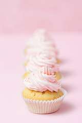 Cupcake decorated with pink buttercream on pastel pink background. Sweet beautiful cake. Vertical banner, greeting card for birthday, wedding, women's day. Close up photography. Selective focus