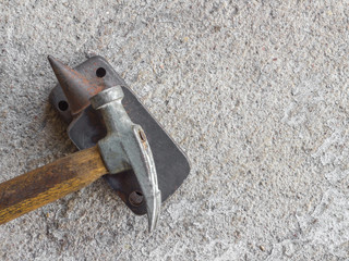 Old small hammer and miniature anvil with concrete background