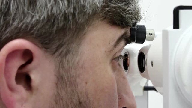 Patient in ophthalmology clinic. Man looks in synoptophore - ophthalmic instrument, used for diagnosing imbalance of eye muscles and treating them by orthoptic methods, for treatment of strabismus