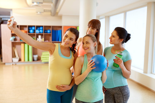 pregnant women taking selfie by smartphone in gym