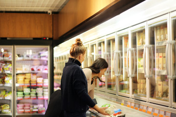 Woman choosing frozen food from a supermarket freezer