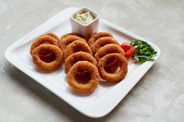 Golden onion rings fried in deep frying. With Sauce on a white plate
