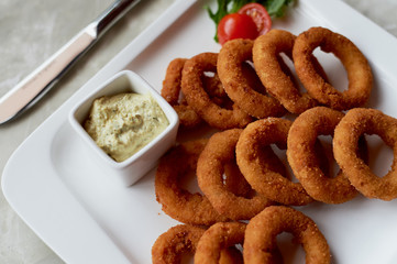 Golden onion rings fried in deep frying. With Sauce on a white plate