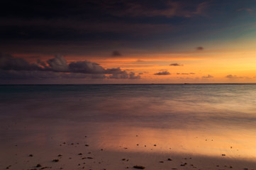 Fototapeta premium A long exposure of the sea at golden hour, as dawn starts to break over a white sandy beach.