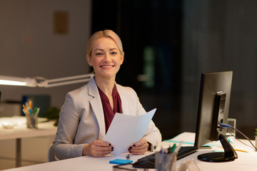 businesswoman with papers working at night office