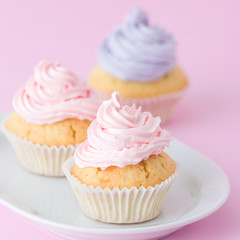 Cupcake decorated with pink and violet buttercream on pastel pink background. Sweet beautiful cake. Square banner, greeting card for birthday, wedding. Close up photography. Selective focus