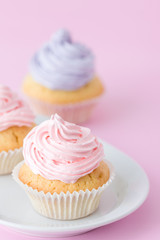 Cupcake decorated with pink and violet buttercream on pastel pink background. Sweet beautiful cake. Vertical banner, greeting card for birthday, wedding. Close up photography. Selective focus