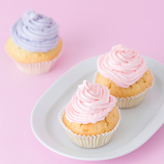 Cupcake decorated with pink and violet buttercream on pastel pink background. Sweet beautiful cake. Square banner, greeting card for birthday, wedding. Close up photography. Selective focus