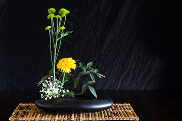 Japanese style flower arrangement ikebana on bamboo mat.