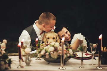 Bride and groom sitting at wedding table and smiling at camera