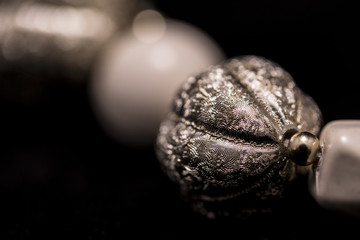 A part of a white bead necklace with gold and silver elements