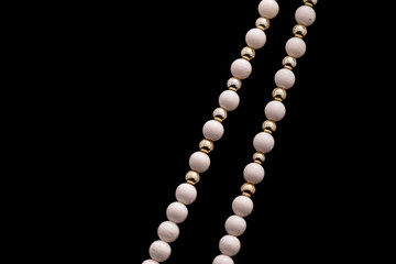 A part of a white bead necklace with gold and silver elements