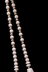 A part of a white bead necklace with gold and silver elements