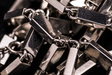 A metal/silver necklace on a dark background.