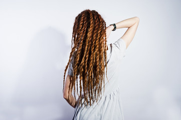 Studio shoot back of girl in gray dress with dreads on white background.