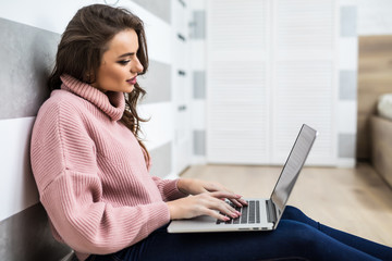 Naklejka premium Young young woman sitting in the floor with laptop.