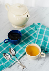 Two teacups and a teapot on a white marble countertop