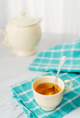 Teapot and teacup on a counter with a green dishtowel