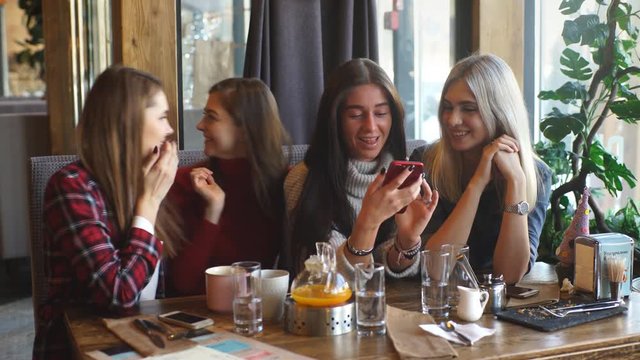 communication and friendship concept - smiling young women with coffee cups at cafe