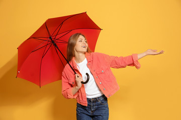 Young woman with red umbrella on color background