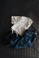 High angle view of folded jeans, t-shirt and tennis shoes on bed - 195549707