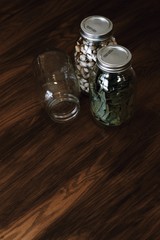 Mason jars with pistachios and bay leaves on dark, wooden table - 195549777