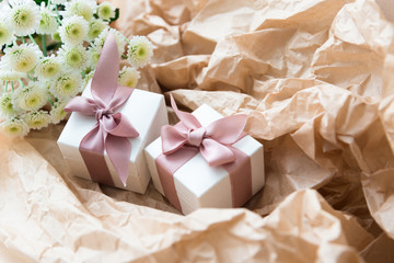 White gift boxes of the famous jewelry brand with charms bracelets with a pink ribbon. Mock up. Empty place for an inscription. Postcard for the holiday. 