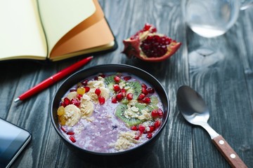 Day planning, time management, healthy food and lifestyle concept. Tasty smoothie bowl with fruits and yoghurt for breakfast on table with paper planner.