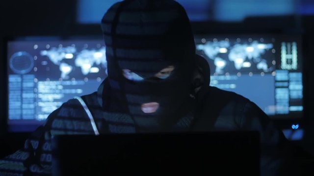 Anonymous hacker in the mask tries to enter the system using codes and numbers to find out the security password. The concept of cybercrime.