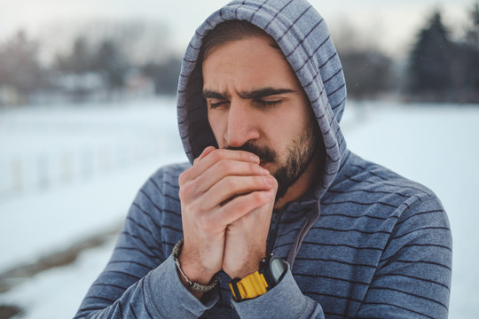 Man warming hands with his breath and preparing to train