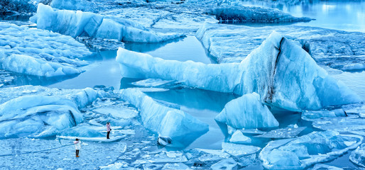 Jokulsarlon Gletscherlagune Panorama im Morgengrauen, in Island. Unidentifizierbare Touristen laufen auf dünnem Eis, um spektakuläre Eisberge zu fotografieren.