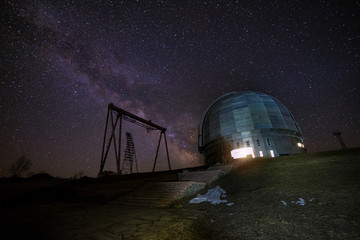 Night view. A special astrophysical observatory and a crane against the background of the starry sky