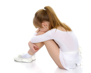 Girl gymnast sits on the floor and cries