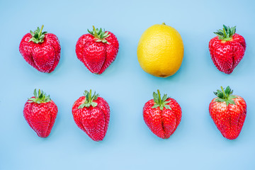 set of strawberries and a lemon in a line on blue background