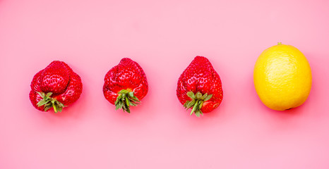 raw of fresh juicy strawberries and a lemon on pink background. flat lay top view