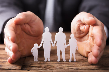 Businessperson's Hand Protecting Family Figures