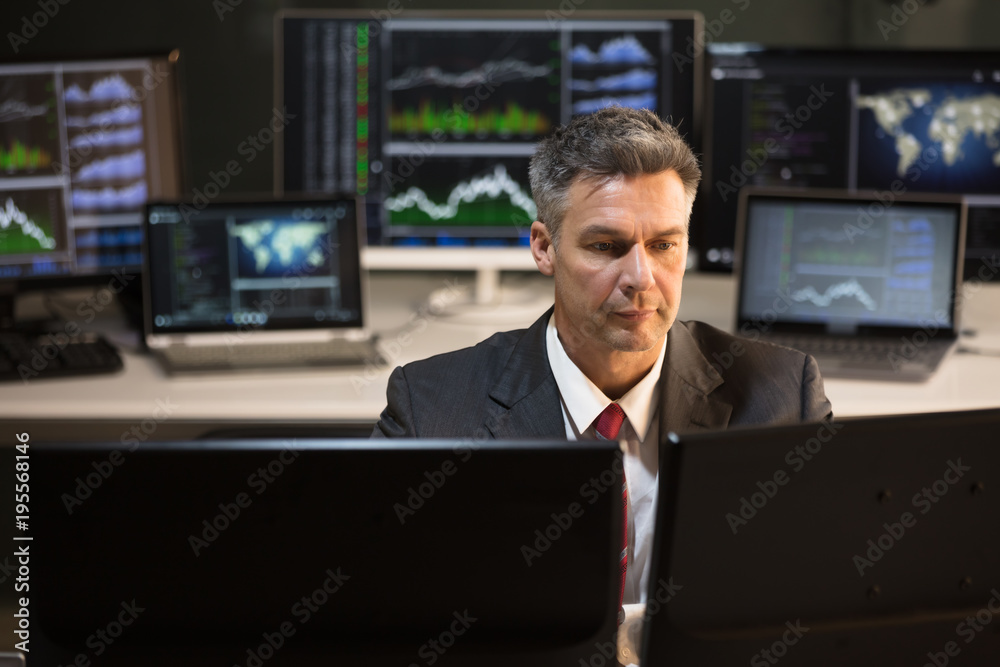 Poster stock market broker looking at multiple computer screen