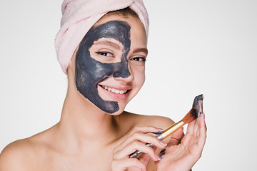 woman on a white background puts on the face a gray mask