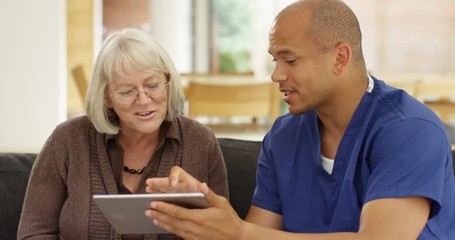 4k, Doctor showing a senior patient some information on a digital tablet in his office. Slow motion