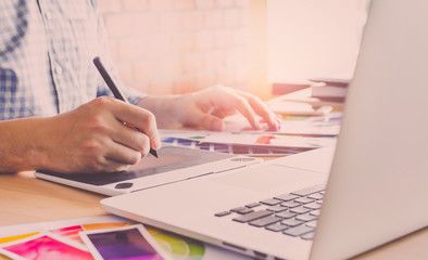 Fototapeta premium Designer graphic creative ,Man holding pen pointing Working on laptop in office with sunset background,Selective focus.