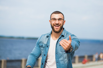 Handsome happy athletic fit man in jeans wear fitness model outdoors copy space. Young male with perfect muscular body poses to camera